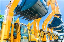 New yellow construction excavators with black buckets in a line